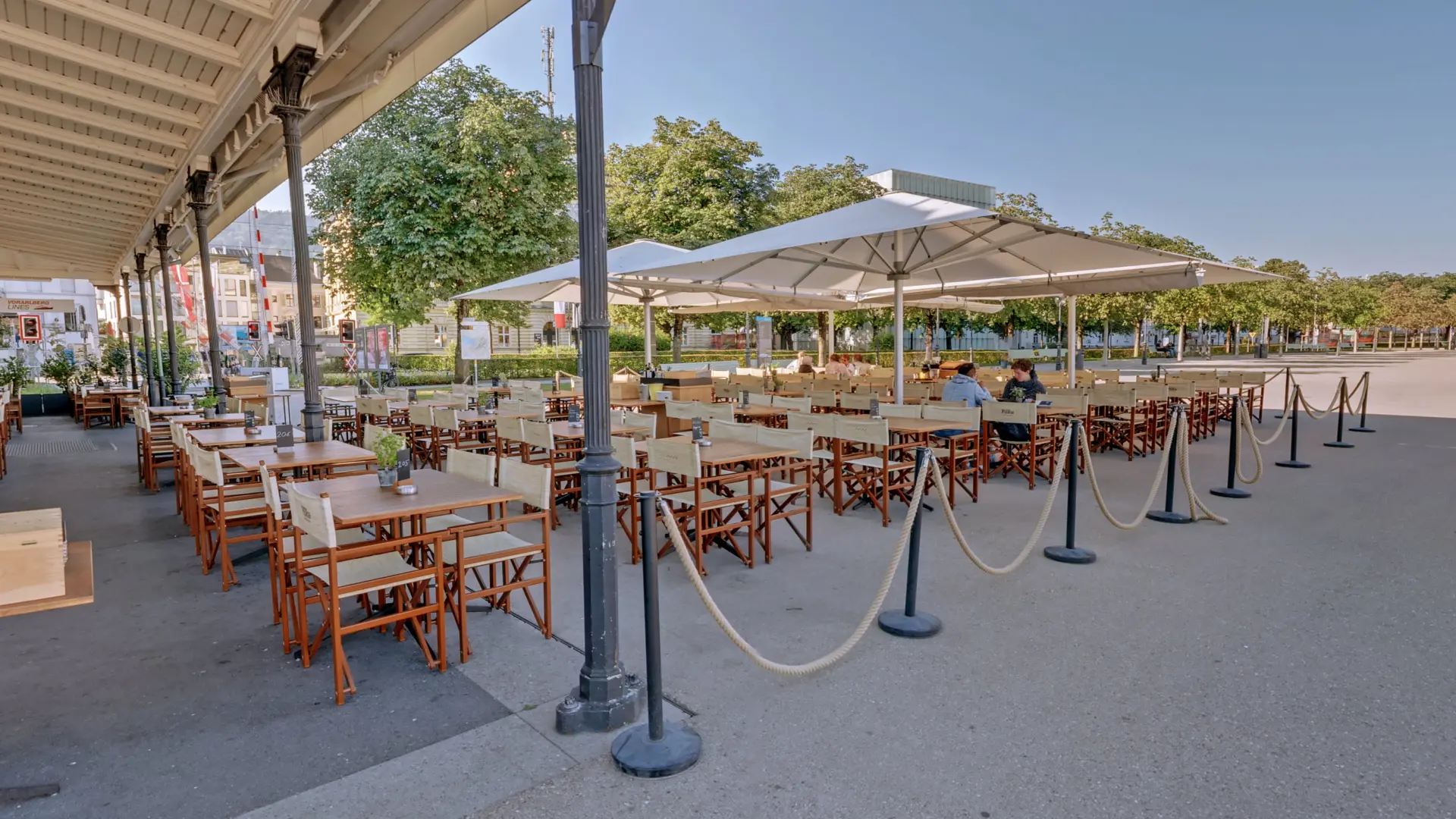 Leerer Außenbereich eines Cafés mit Sonnenschirmen.