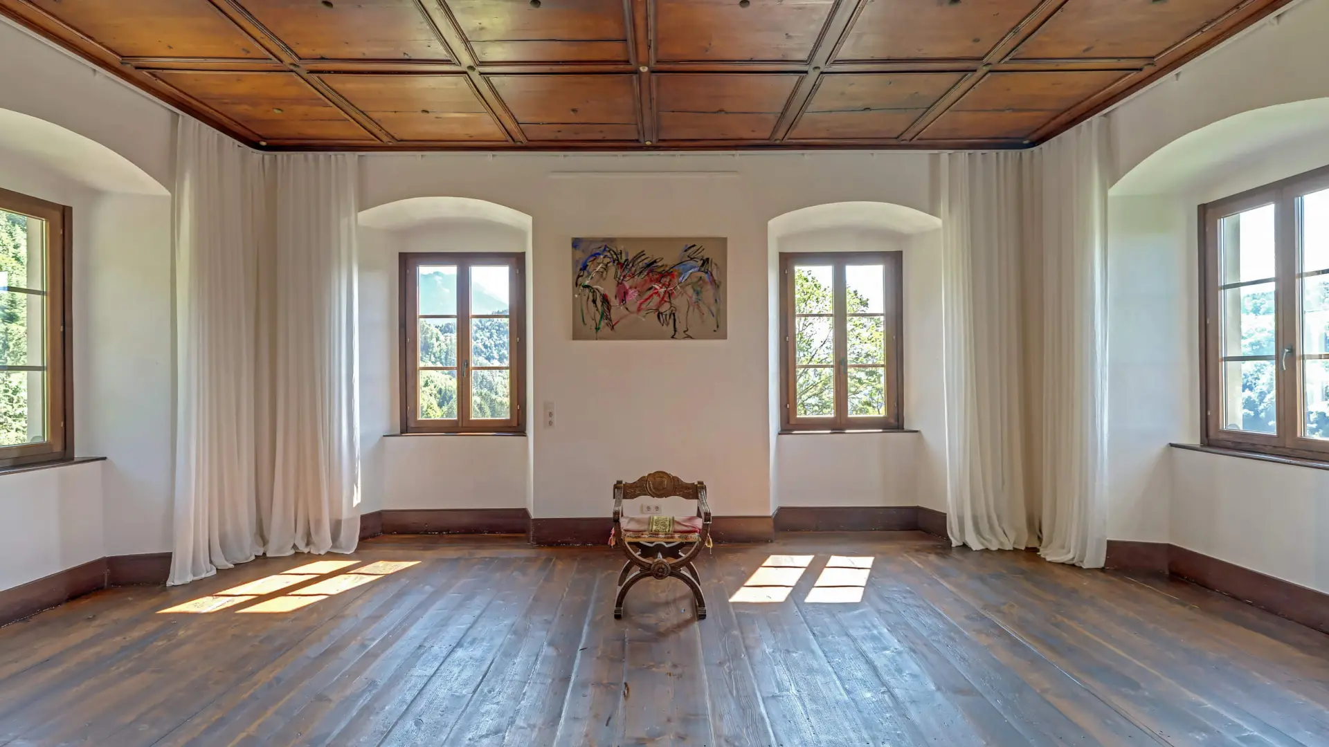 Leerer Raum mit Holzboden und Fenstern.