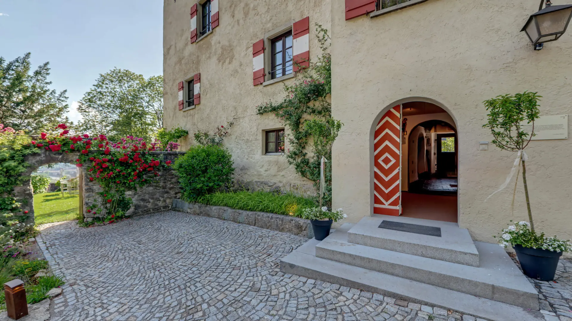 Eingang und Garten eines historischen Gebäudes.