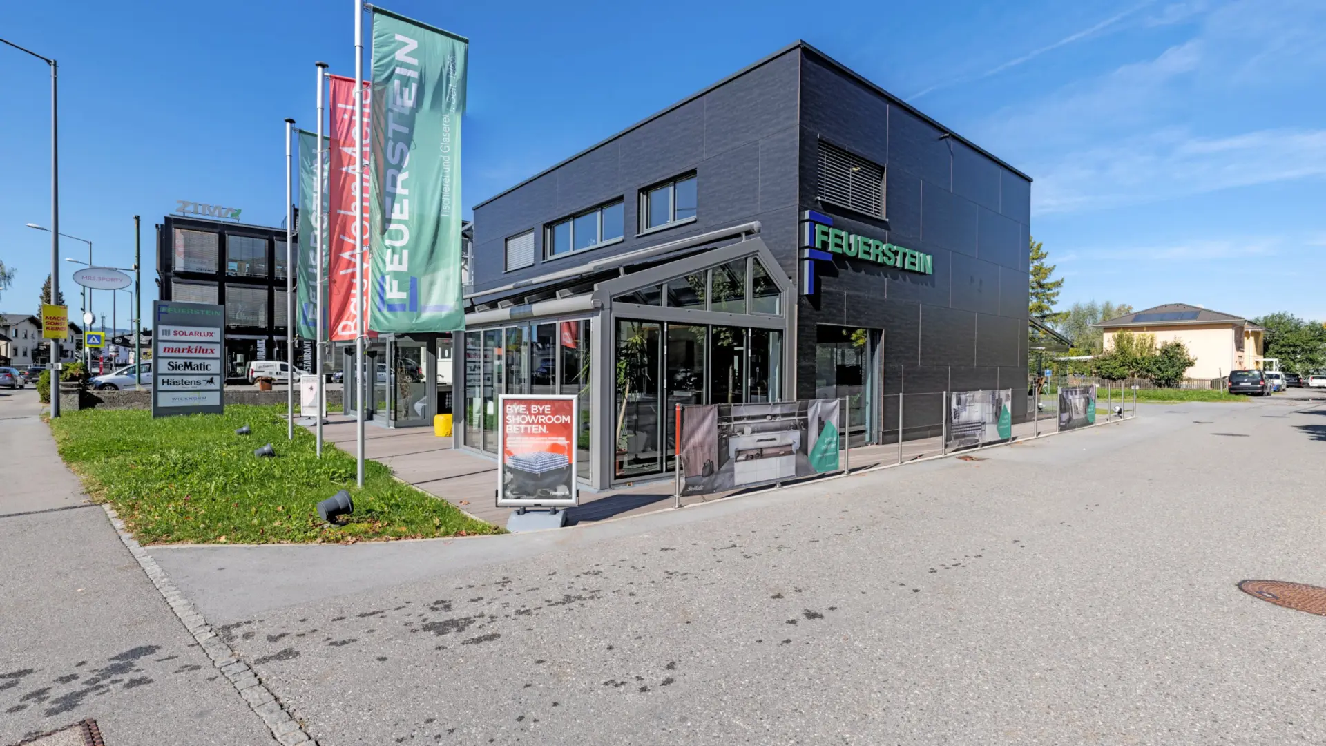 Moderner Showroom mit Firmenlogo und Fahnen im Freien.