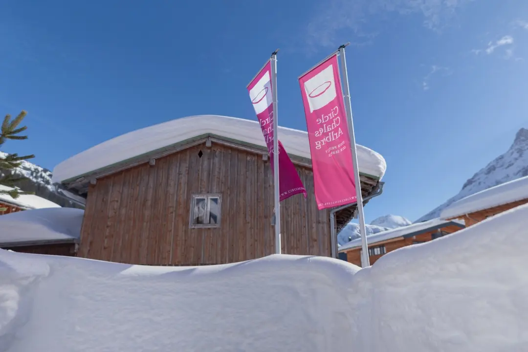Verschneite Holzfassade mit pinken Fahnen