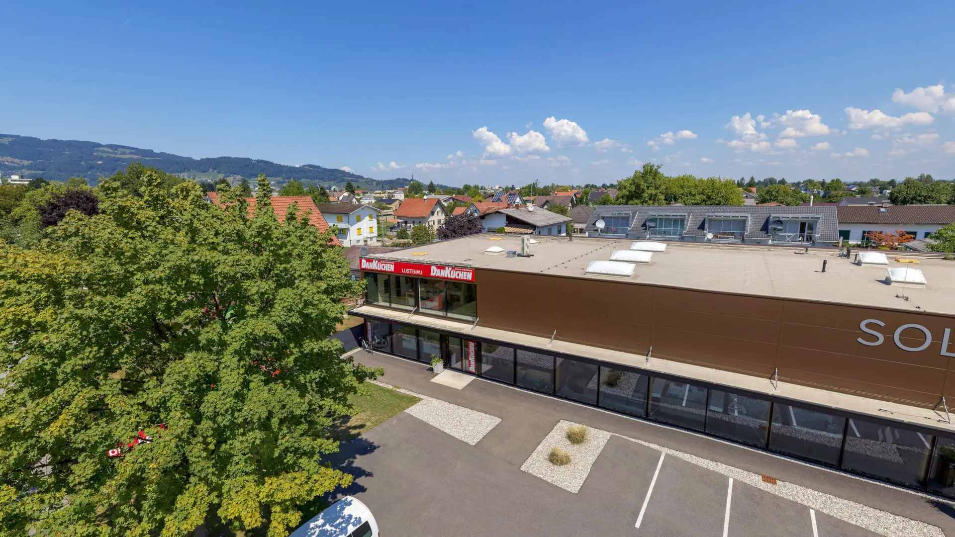 Geschäftsgebäude mit Parkplatz und grünem Baum