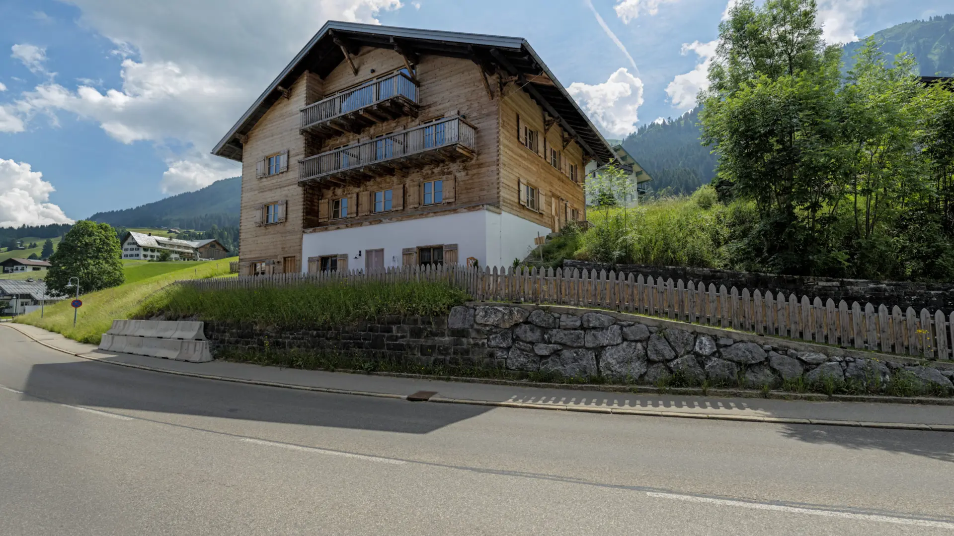 Holzhaus in bergiger Landschaft bei Sonnenschein