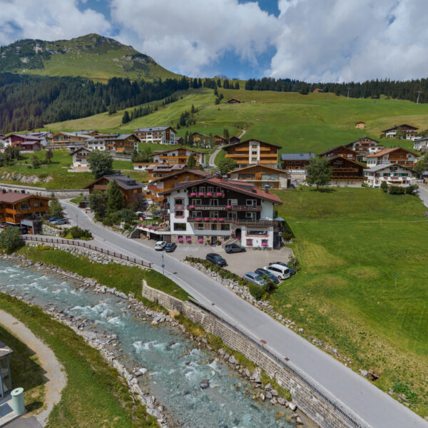 Alpenlandschaft mit Fluss und Holzhäusern in den Bergen.