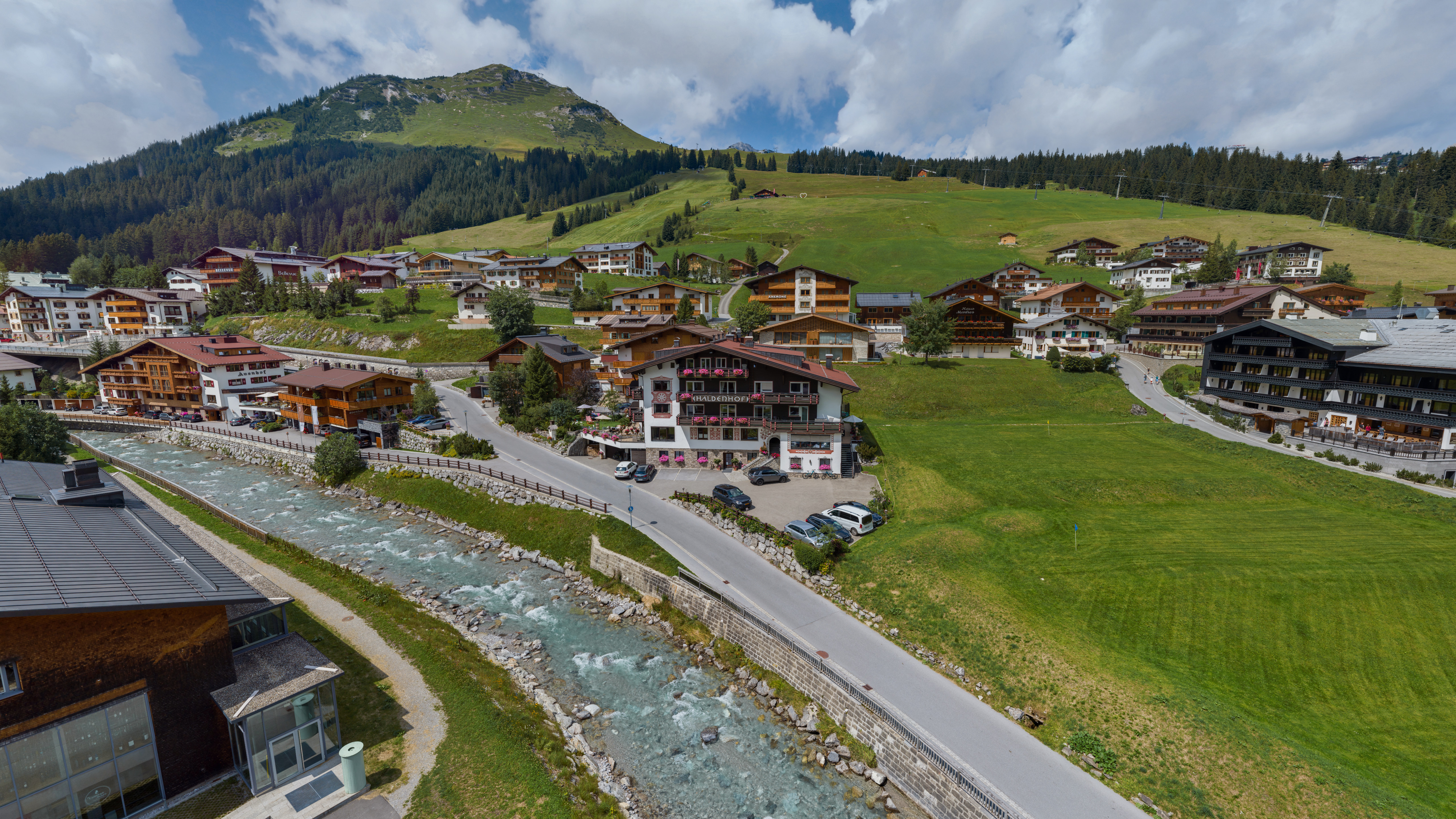 Alpenlandschaft mit Fluss und Holzhäusern in den Bergen.