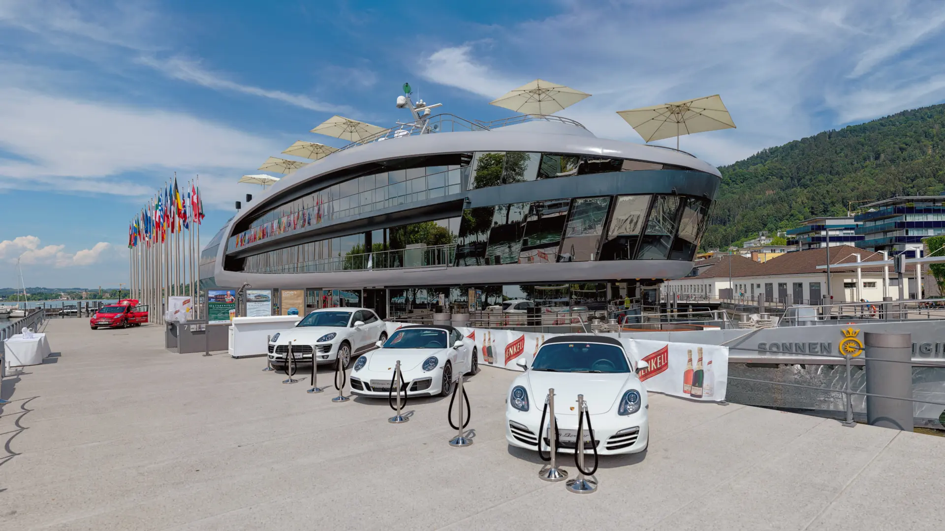 Moderne Architektur mit ausgestellten Sportwagen und Flaggen.