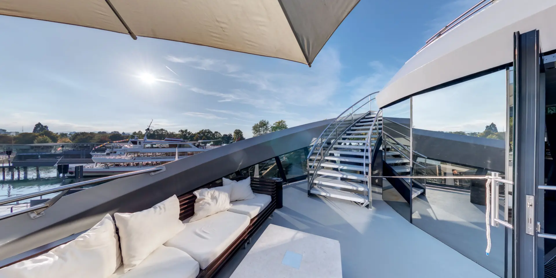 Sonnendeck mit Sofas und Treppe auf einer Yacht.