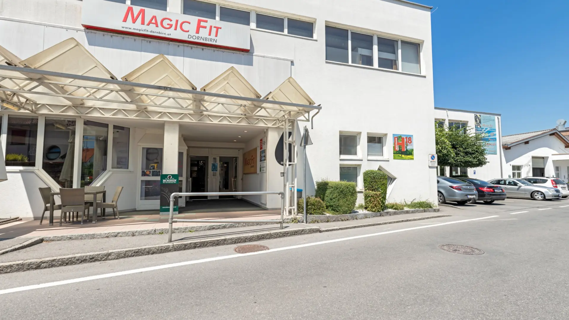 Fitnessstudio-Gebäude mit Parkplatz und Eingang.