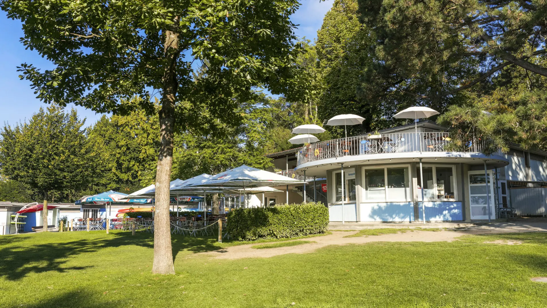 Biergarten im Grünen mit Sonnenschirmen.