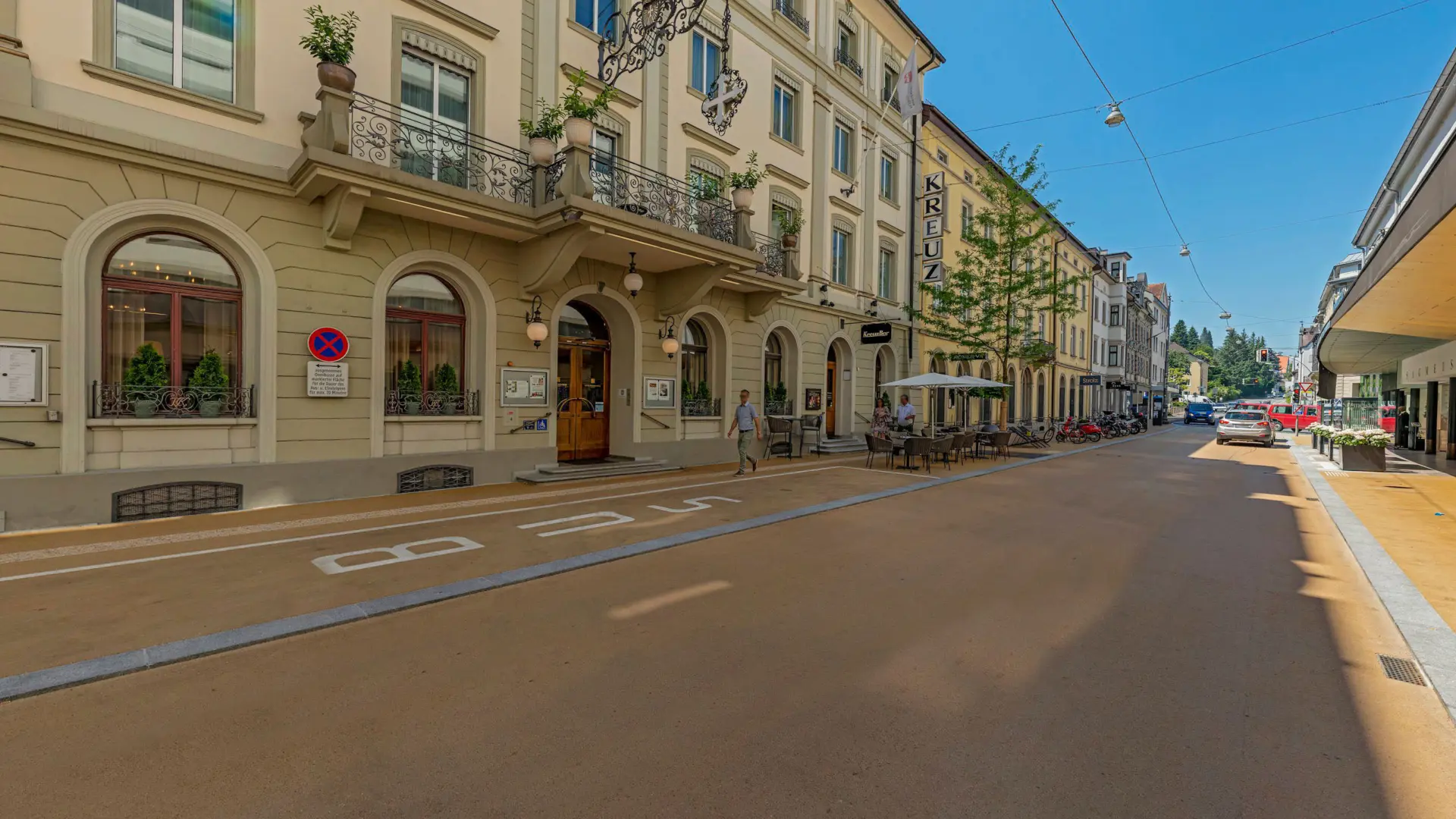 Straßenszene mit historischem Gebäude und Außengastronomie.
