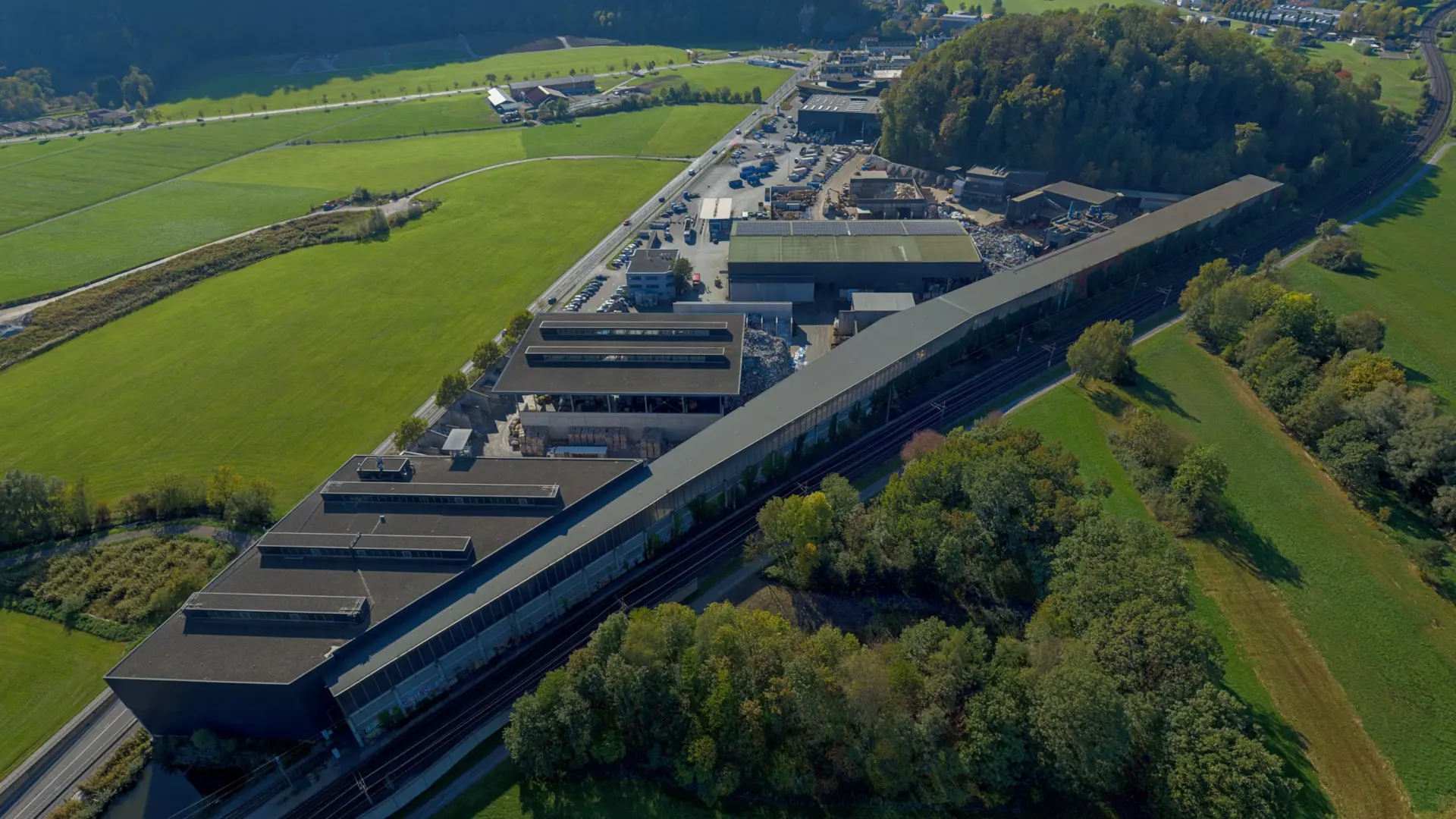 Industriegelände mit umliegenden Feldern und Wald.