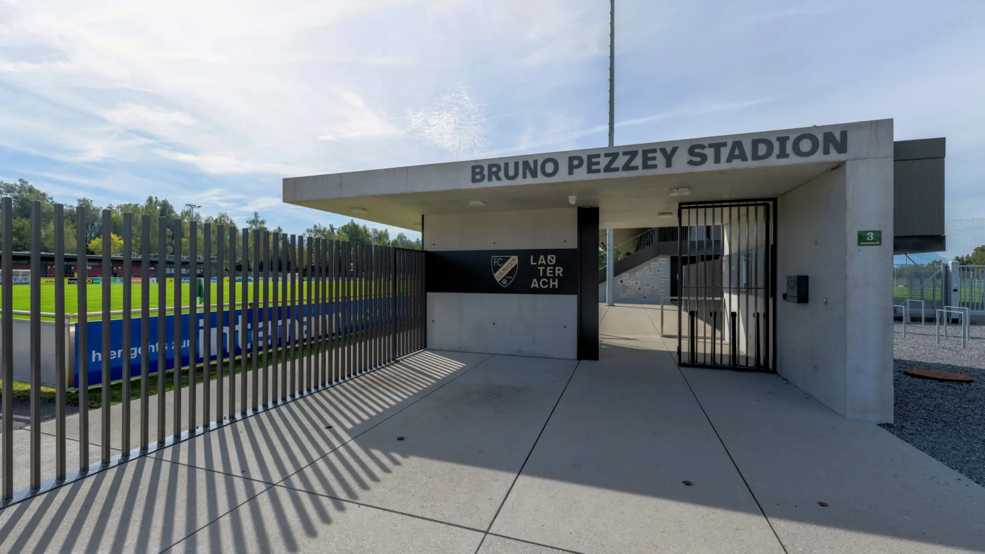 Eingang des Stadions mit Tor und Rasenfläche.