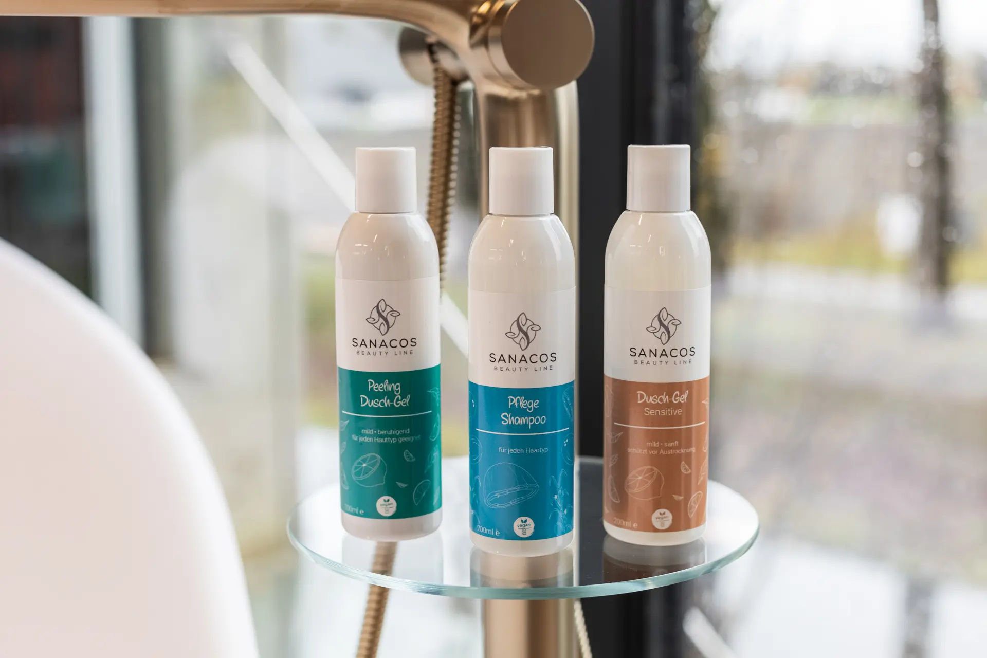 Drei Pflegeprodukte auf Glasablage, modernem Badezimmerhintergrund.