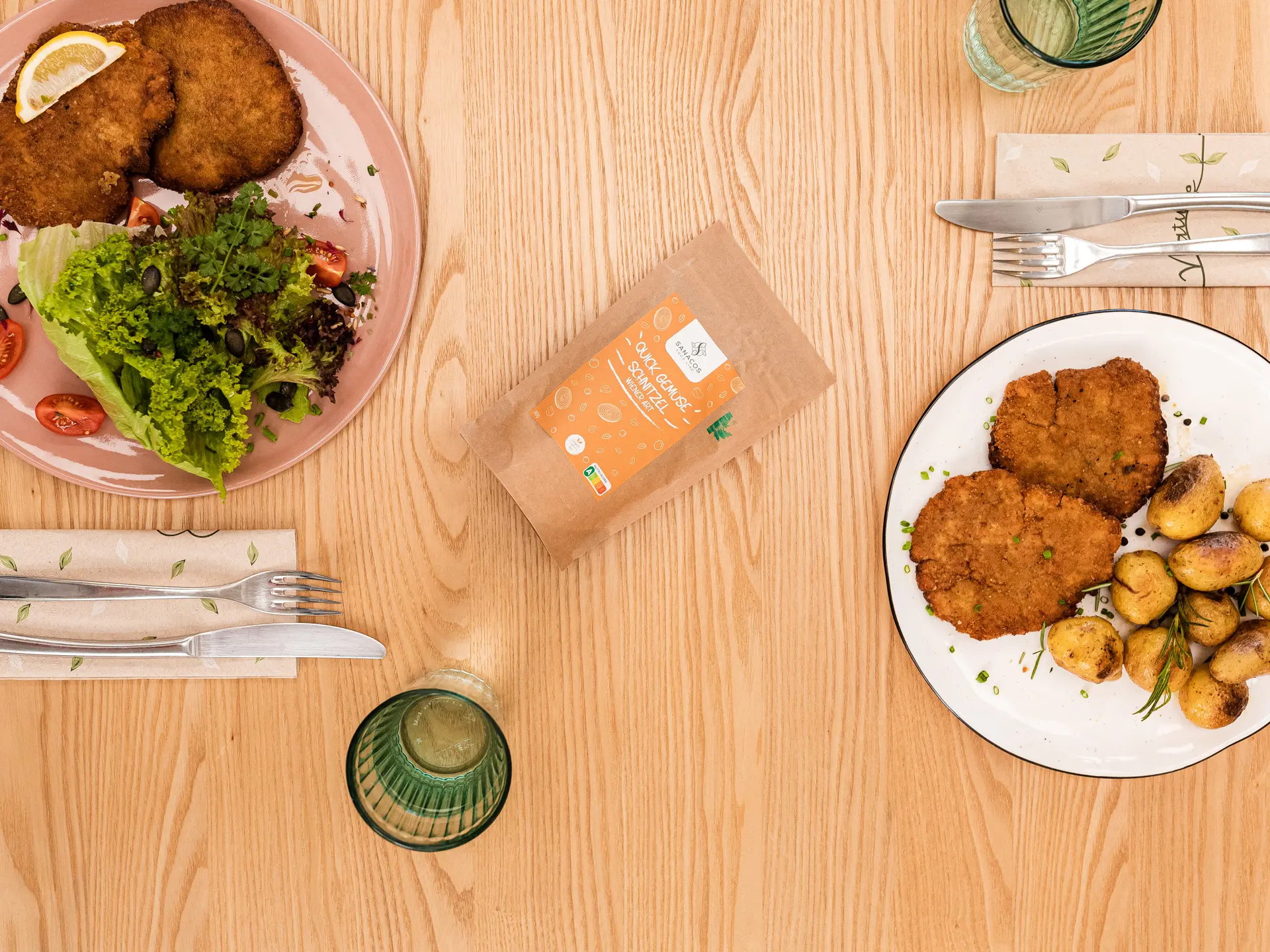 Schnitzel mit Salat und Kartoffeln auf Holztisch.