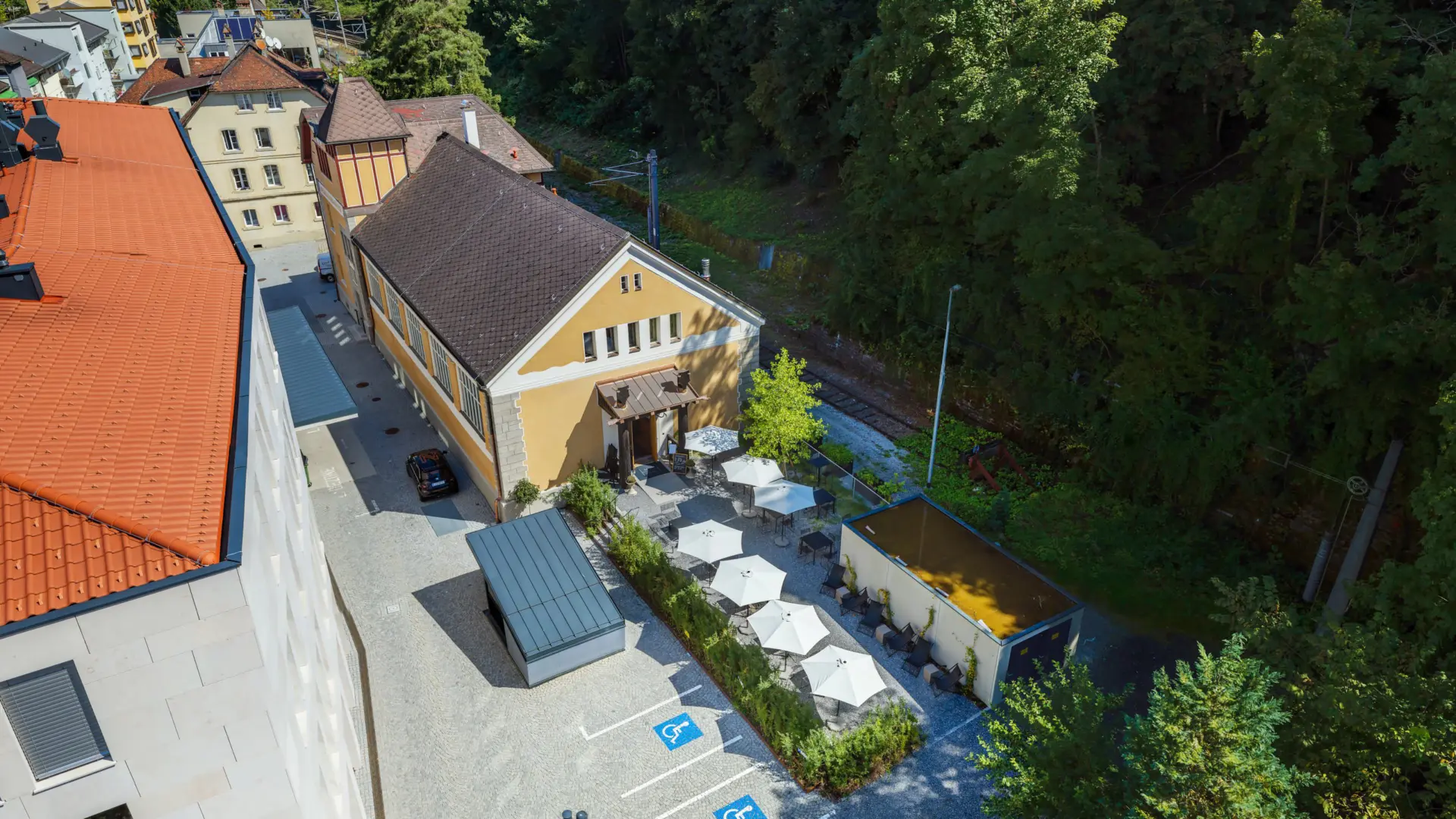 Luftbild eines Gebäudekomplexes mit Terrasse und Parkplatz.