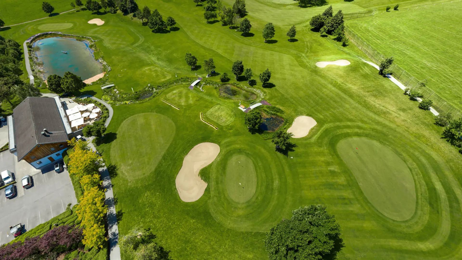 Luftaufnahme eines Golfplatzes mit Teichen und Bäumen.