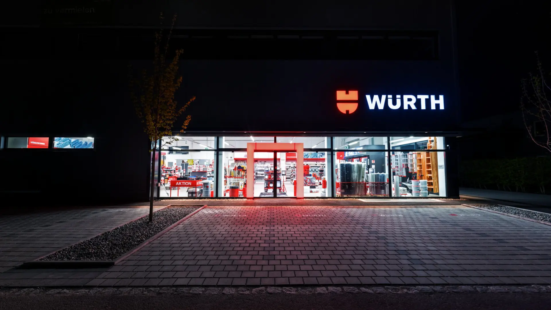 Eingangsbereich eines beleuchteten Fachgeschäfts bei Nacht.