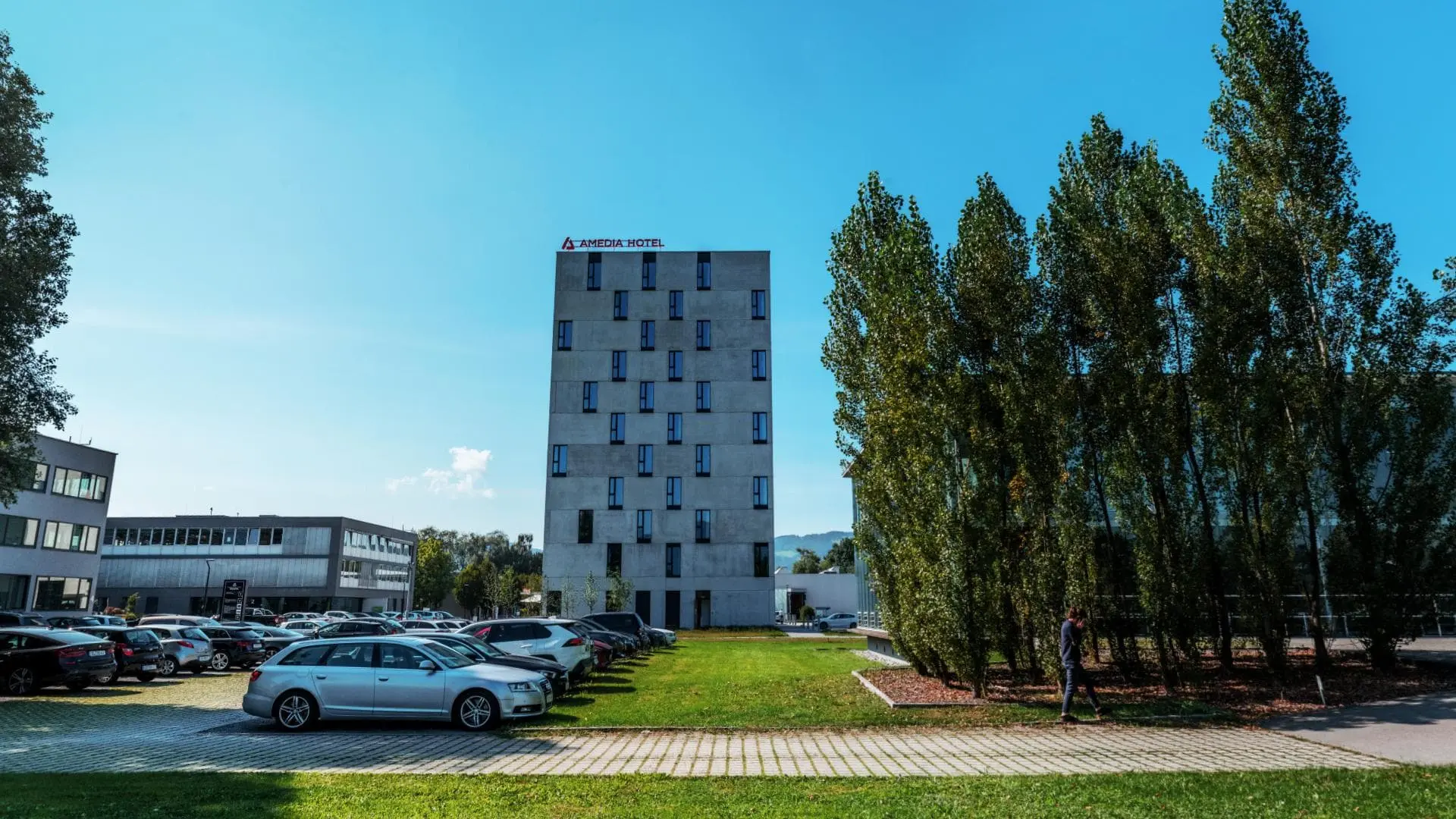 Hotelgebäude mit Parkplatz und Bäumen.