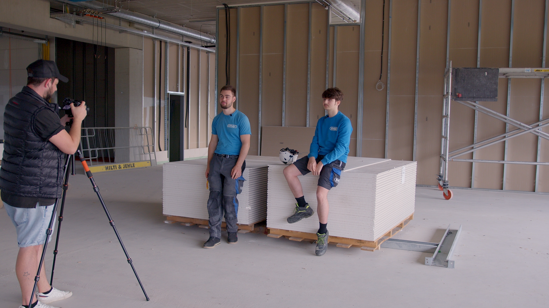 Fotograf fotografiert zwei Bauarbeiter im leeren Raum.