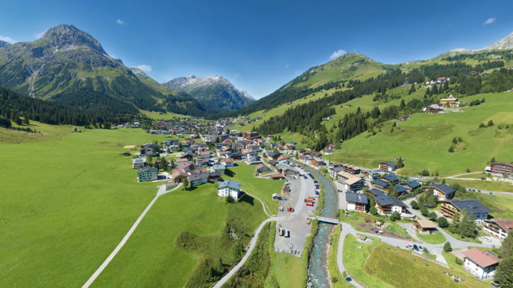 Bergdorf mit Wiesen und Fluss im Sommer.