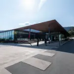 Modernes Gebäude mit Glasfront in sonniger Landschaft.