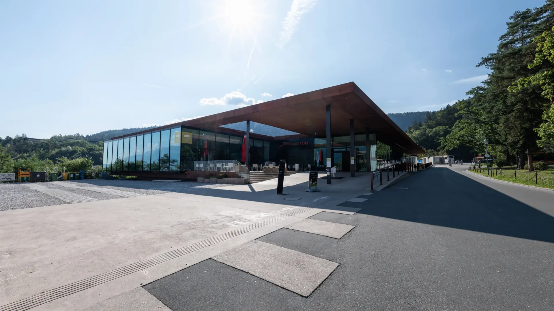 Modernes Gebäude mit Glasfront in sonniger Landschaft.