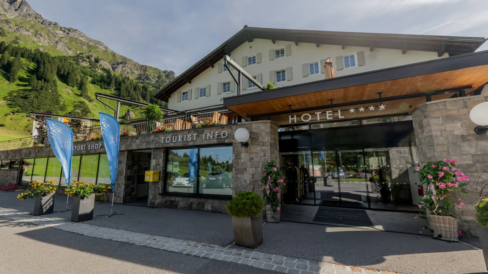 Hotelgebäude mit Bergblick und blauen Fahnen.