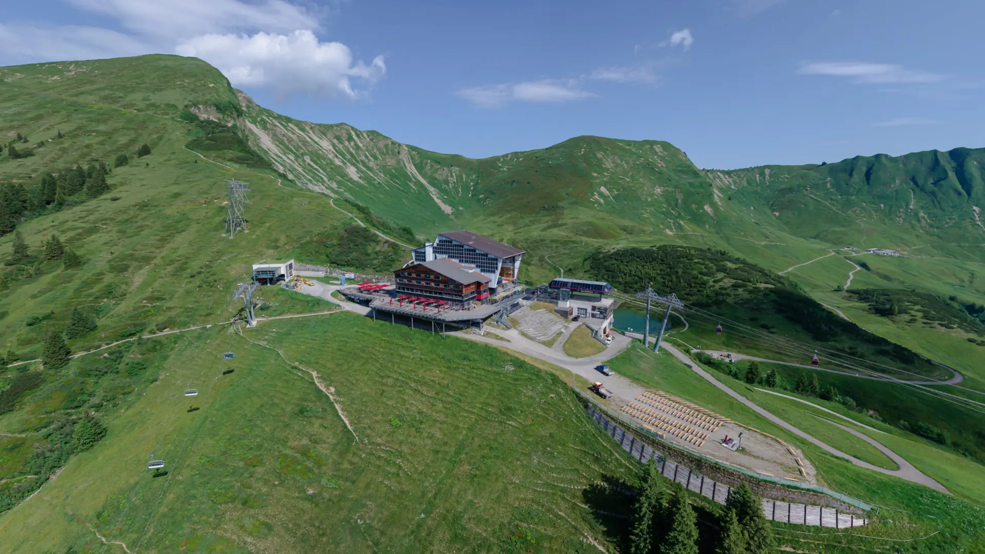 Berglandschaft mit Seilbahn und Bergstation im Grünen.