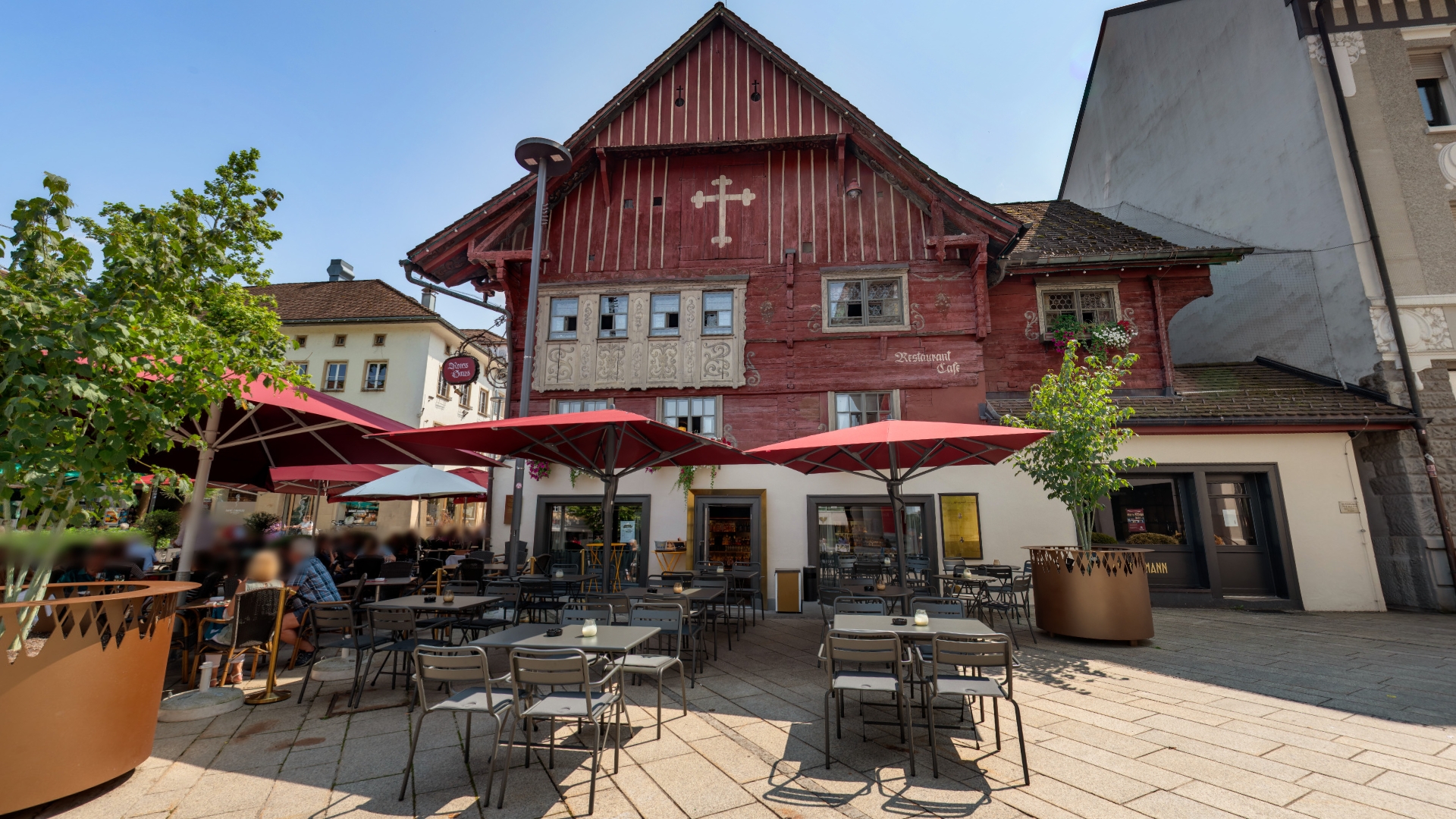 Historisches Gebäude mit Straßencafé und roten Sonnenschirmen