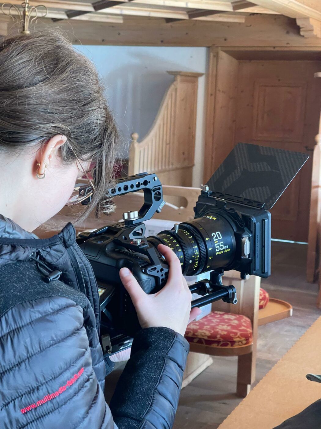 Person bedient professionelle Filmkamera in Holzzimmer.
