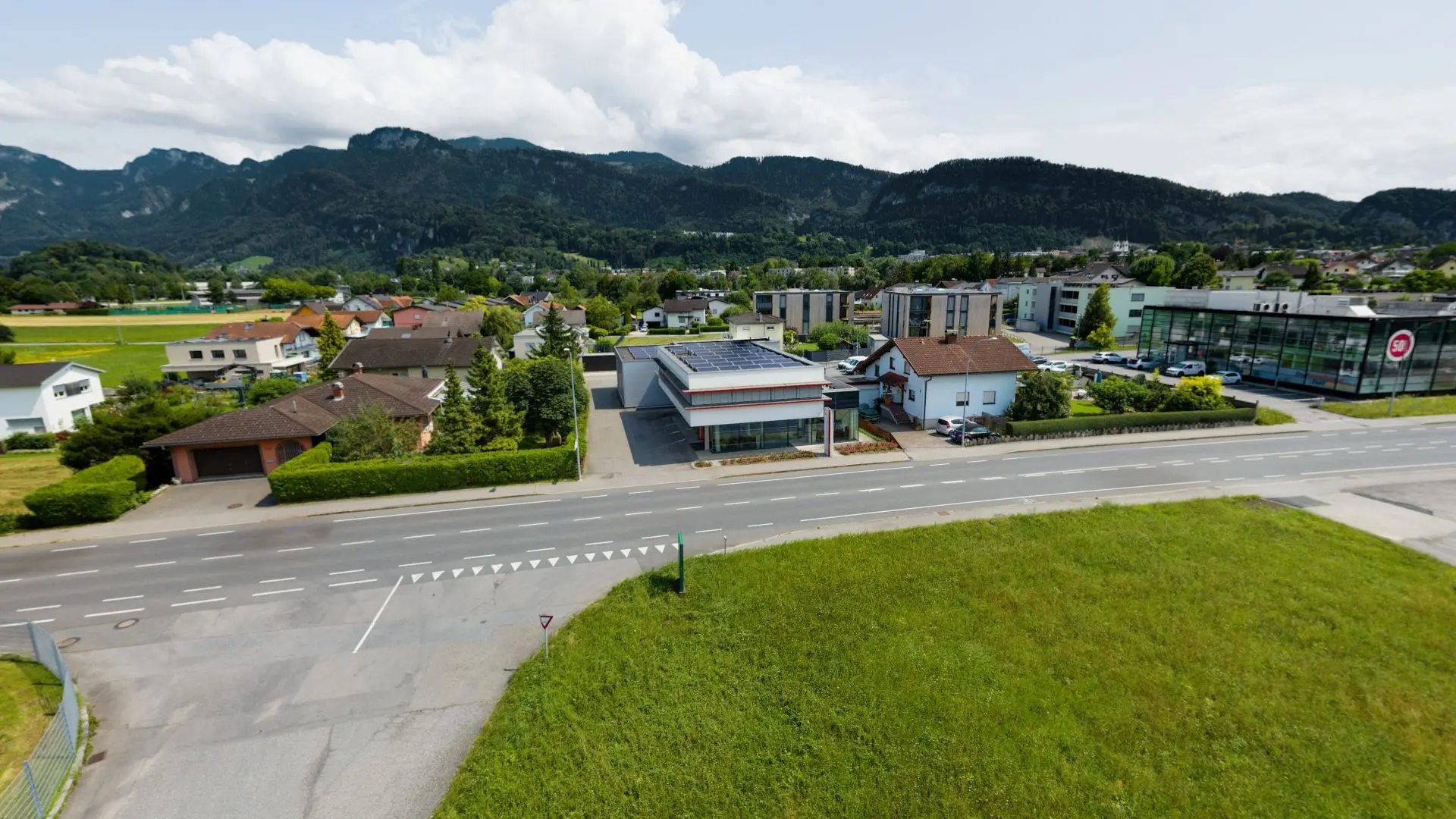 Landschaft mit Straßen und Gebäuden, Berge im Hintergrund.