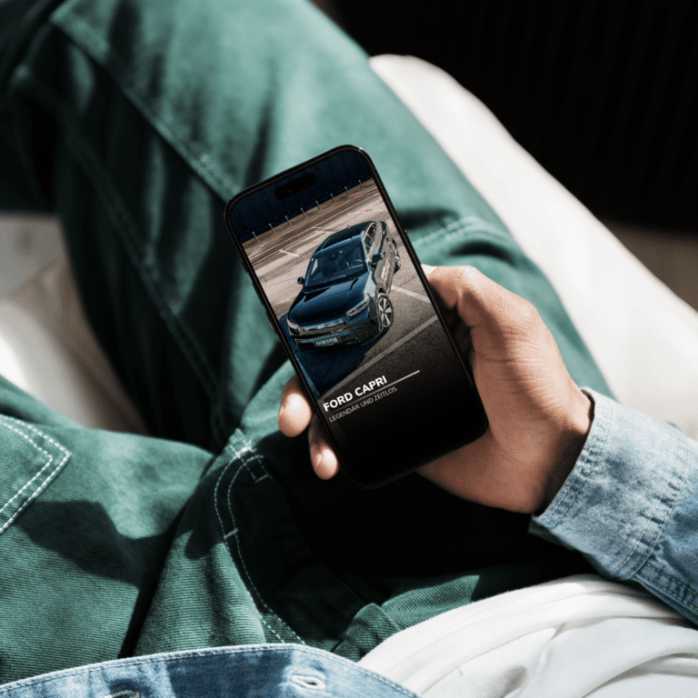 Person hält Smartphone, zeigt Ford Capri Automobilbild.