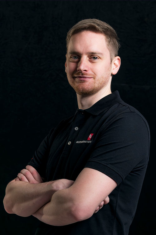 Mann in schwarzem Poloshirt mit verschränkten Armen.