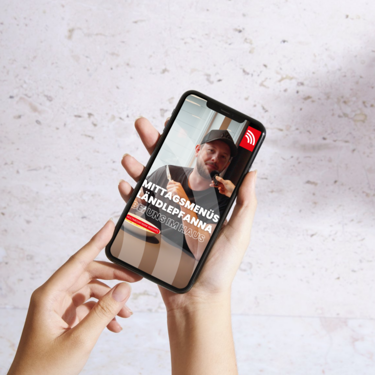 Hand hält Smartphone mit Mittagsmenü-Werbung.