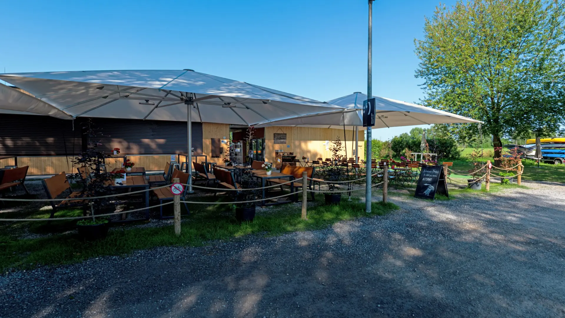Gemütlicher Biergarten mit Sonnenschirmen im Freien.