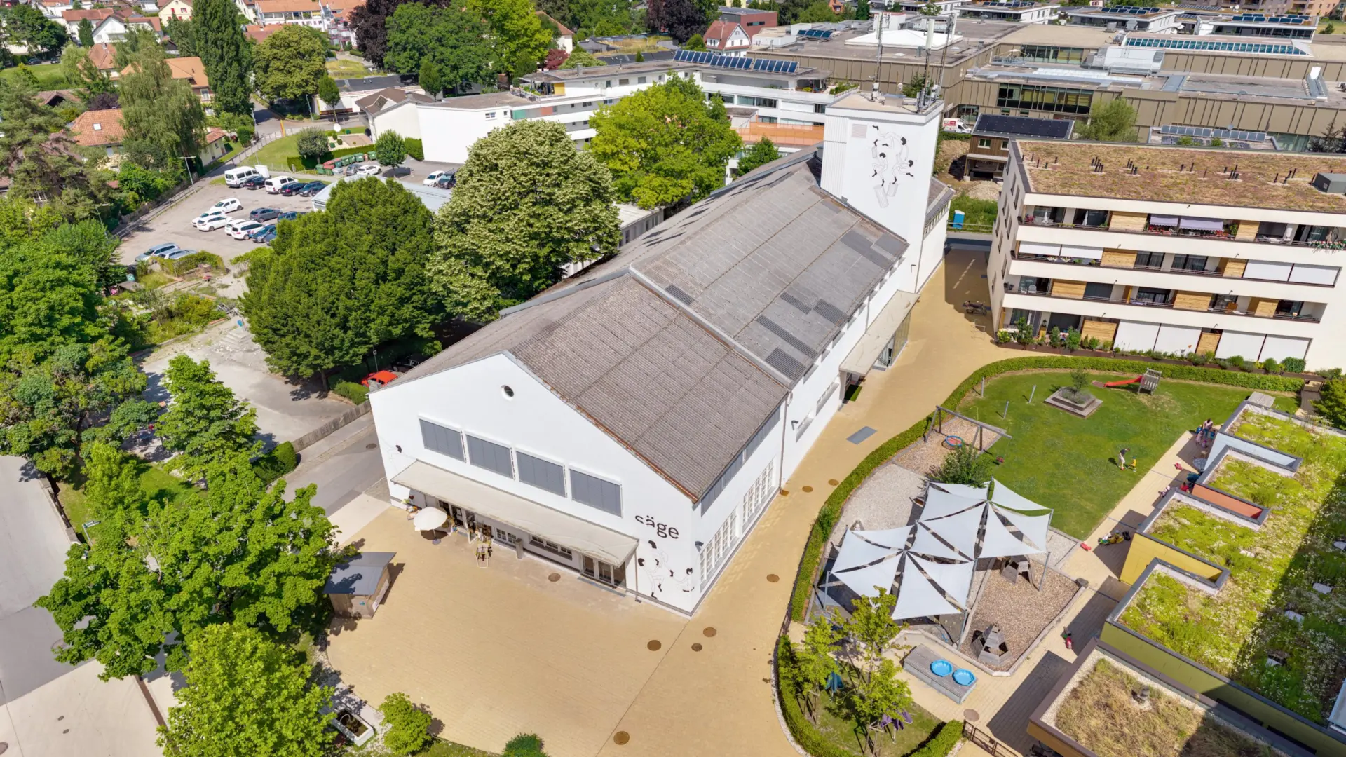 Luftaufnahme eines modernen Gebäudekomplexes mit Grünfläche.