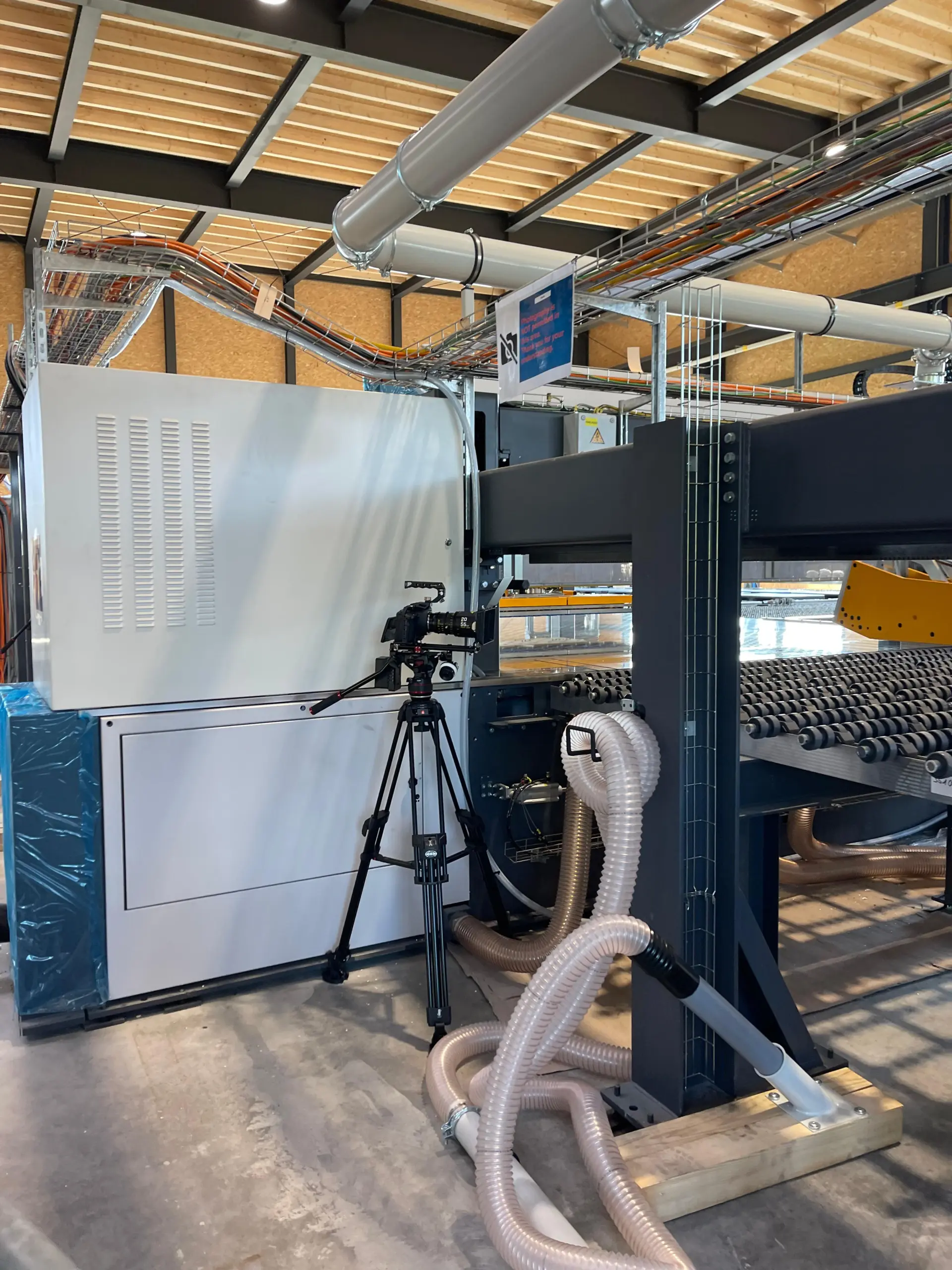 Kamera auf Stativ neben großer Industrieanlage