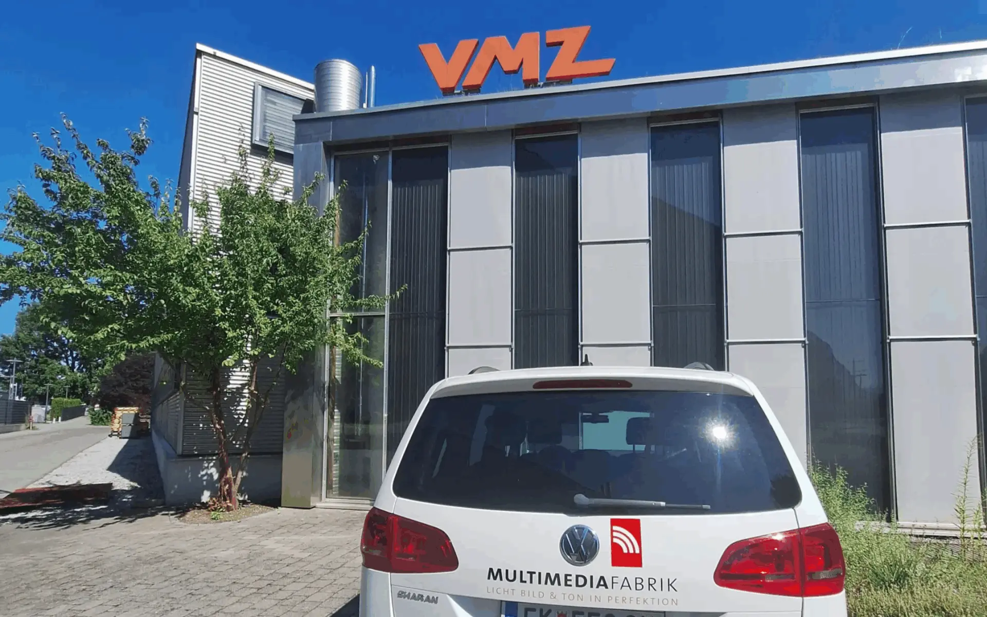 Gebäude mit VMZ-Logo und Auto im Vordergrund.