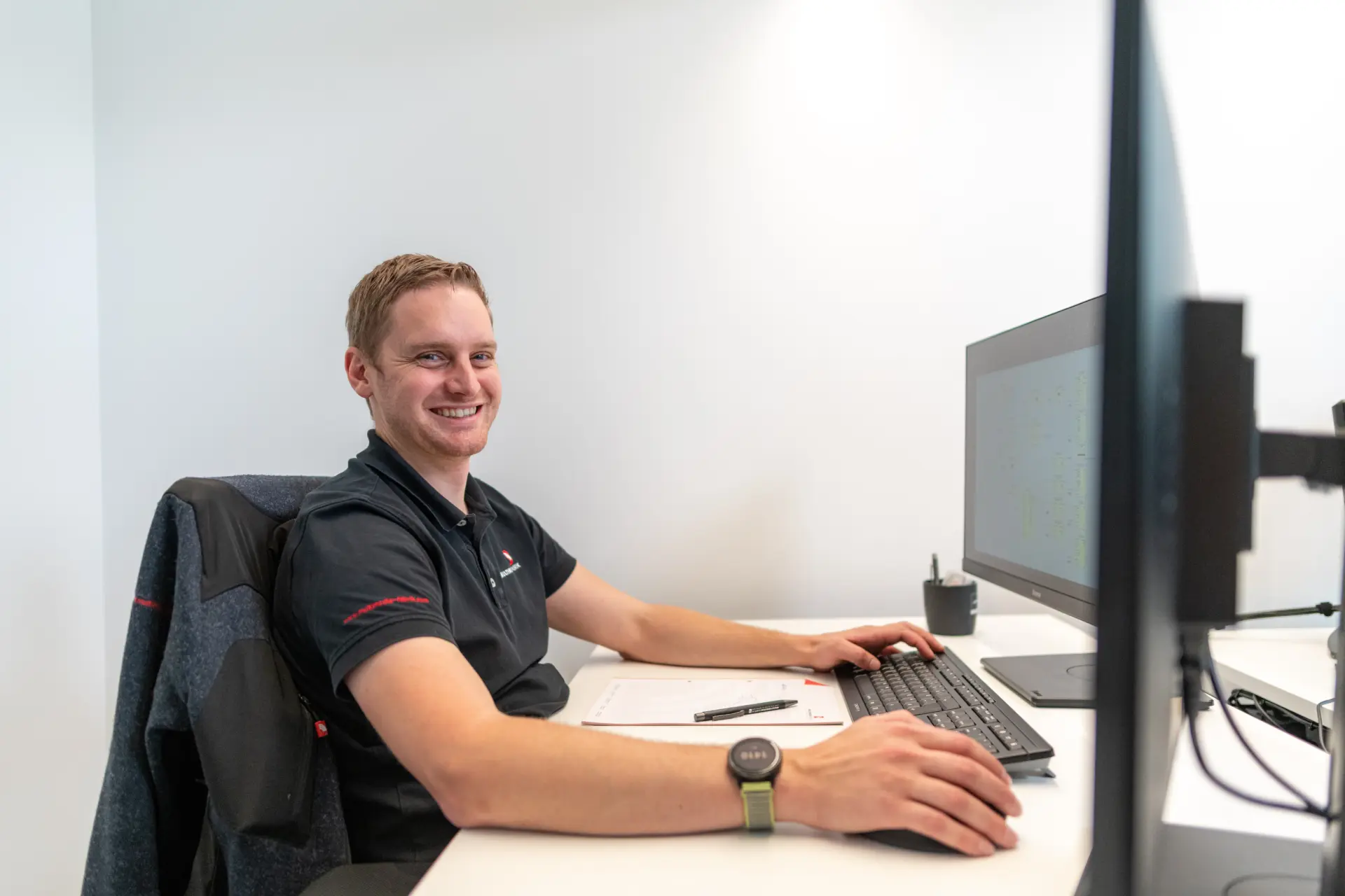 Mann lächelt am Schreibtisch mit Computer.