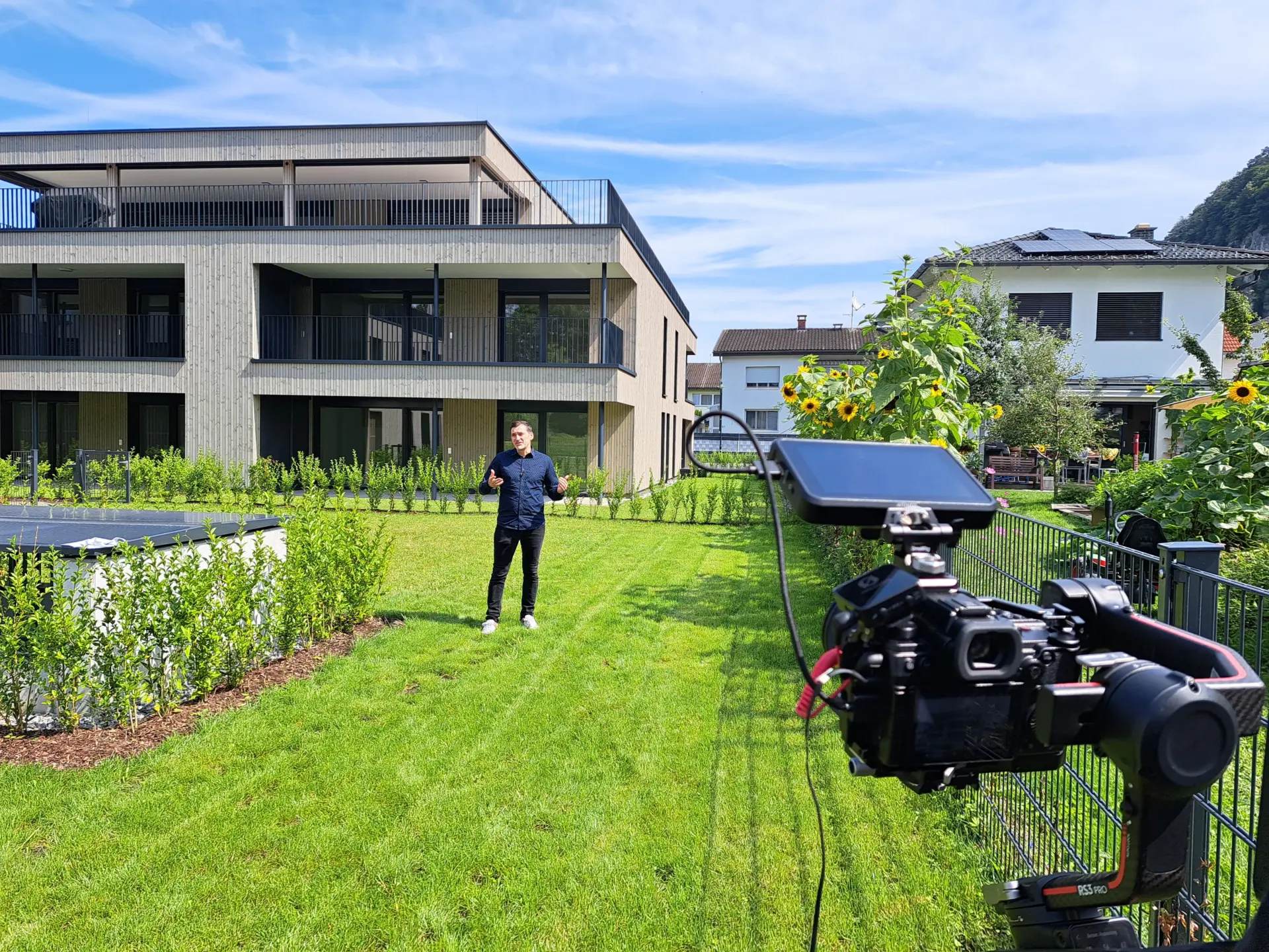 Kamera filmt Mann vor modernen Gebäuden im Garten.
