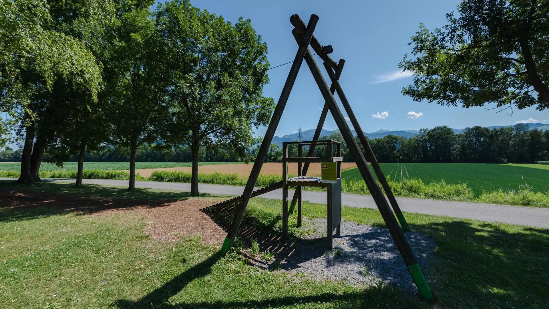 Seilrutsche im Park mit Bäumen und Wiese.