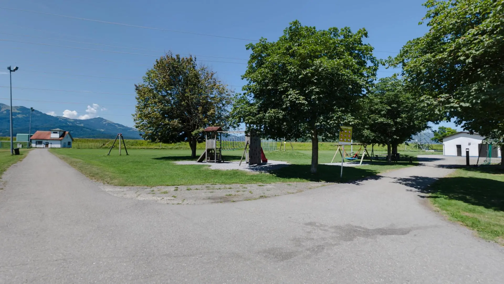 Spielplatz mit Bäumen und Wegen im Sommer.
