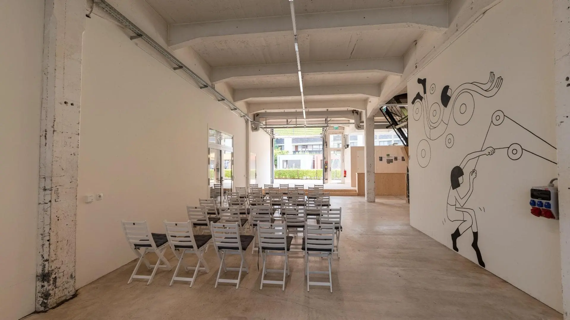 Leerer Veranstaltungsraum mit Stühlen und Wandgemälde.