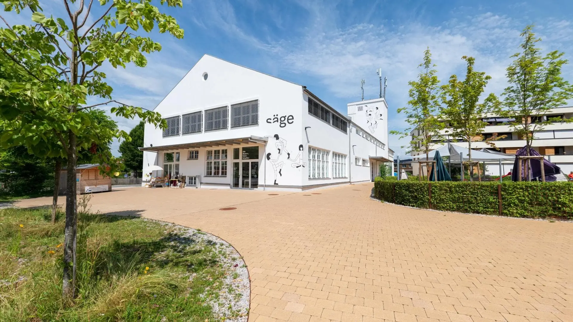 Modernes Gebäude mit Bäumen und hellem Himmel.