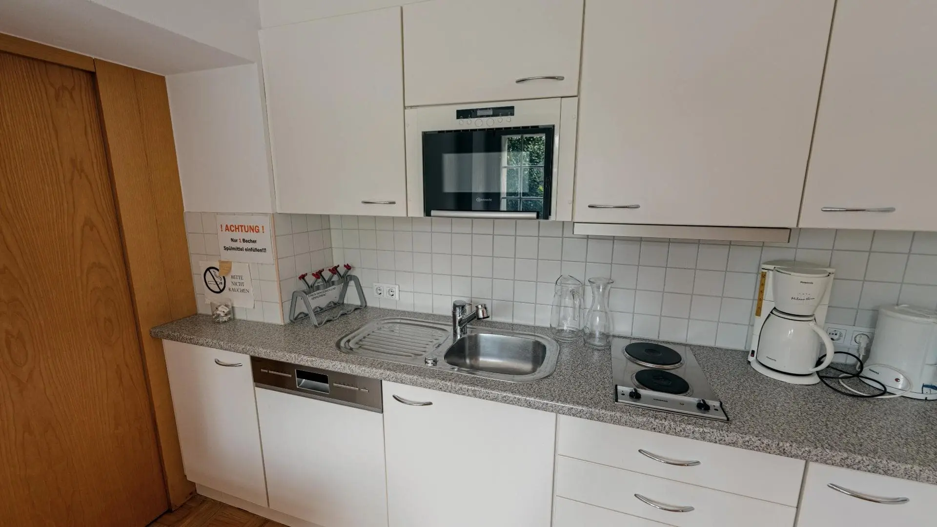 Moderne weiße Küche mit Spüle und Geräten.