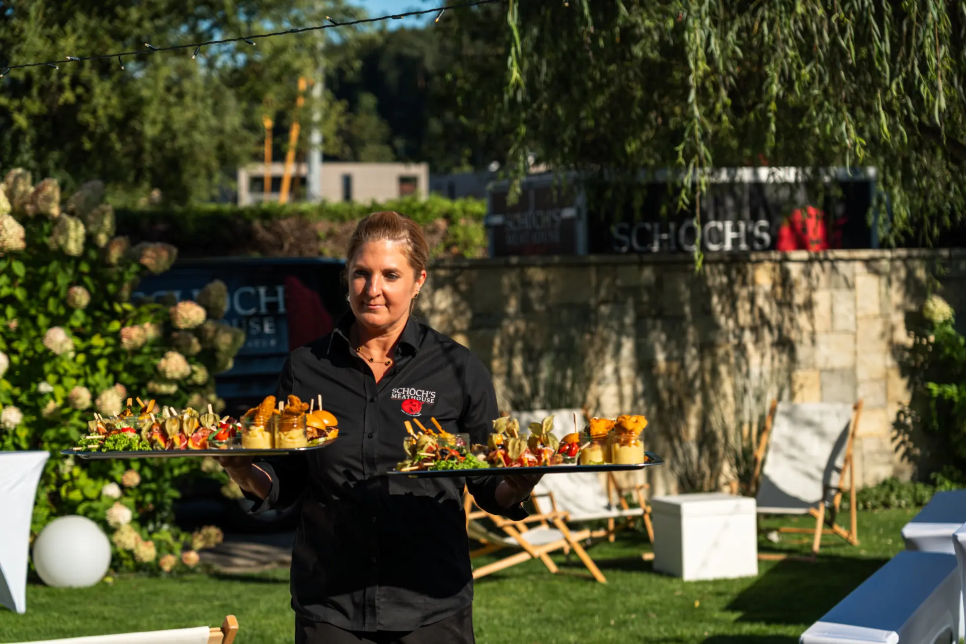 Kellnerin serviert Platten im Garten