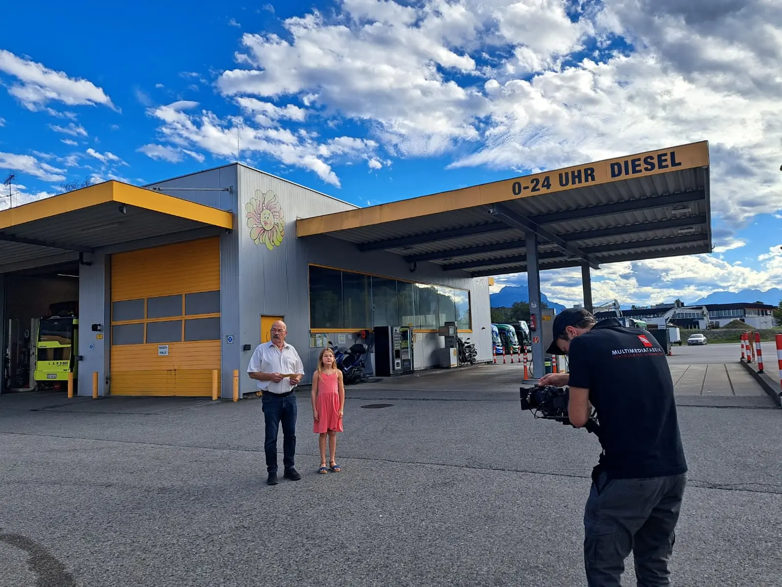 Tankstelle mit Menschen und Kameramann