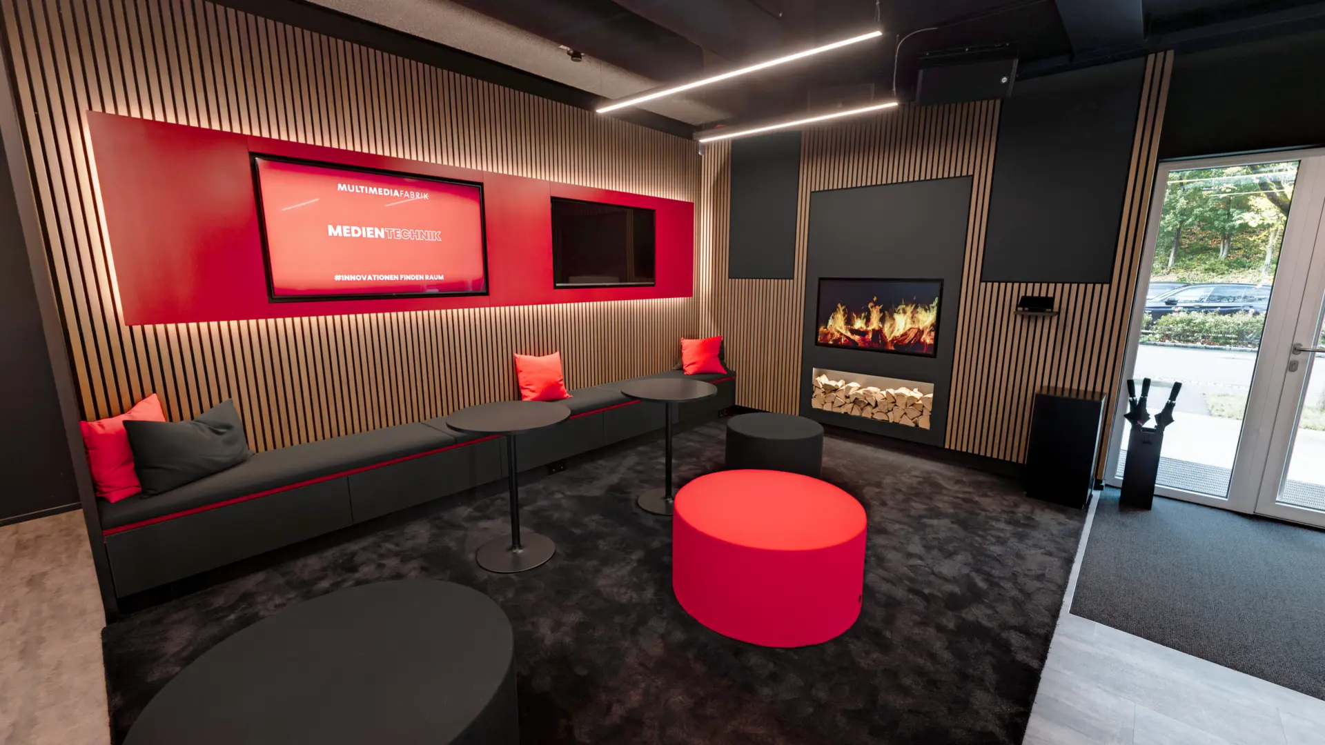 Moderner Loungebereich mit Bildschirm und Kamin.