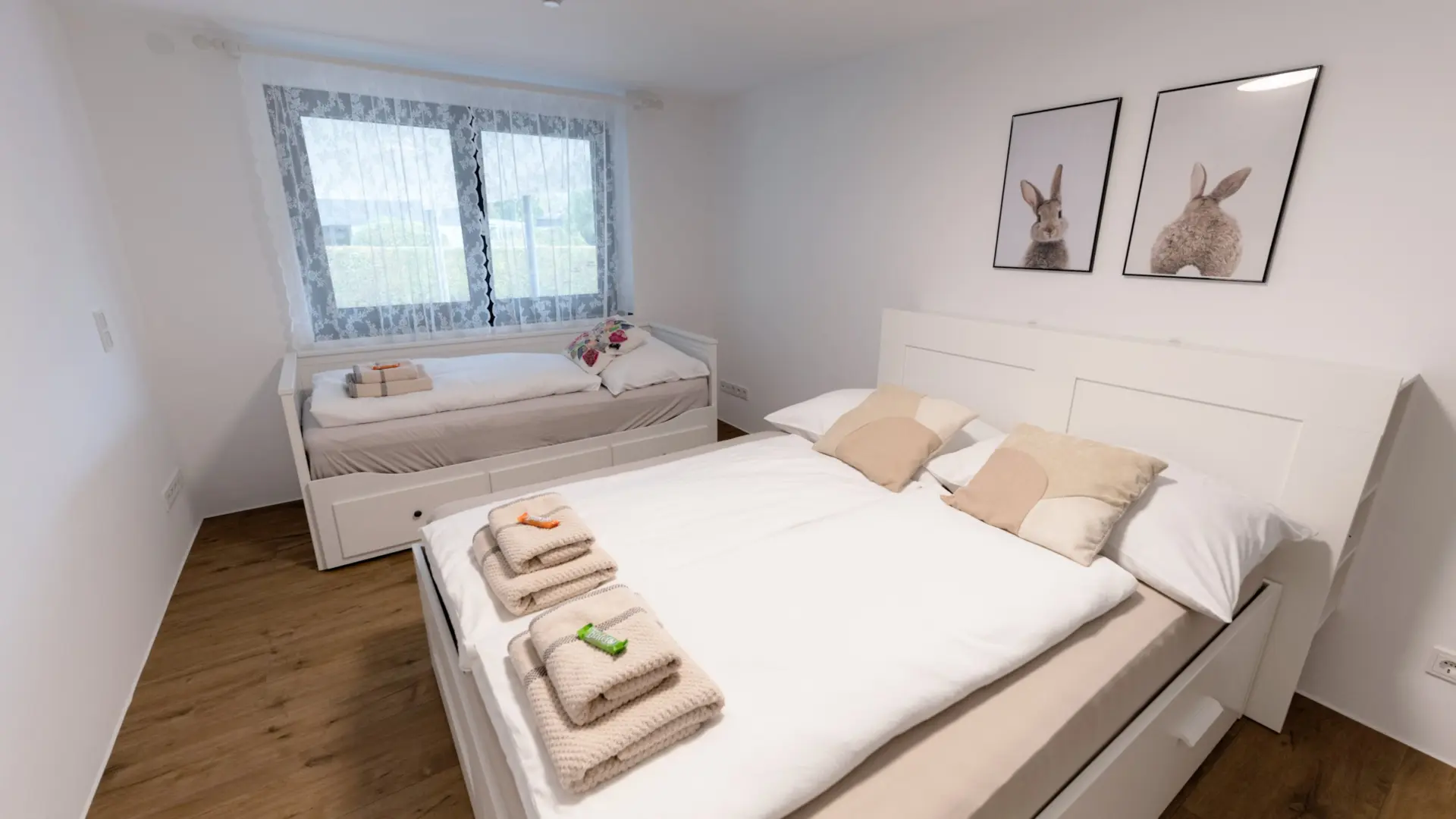 Schlafzimmer mit zwei Betten und Hasenbildern.