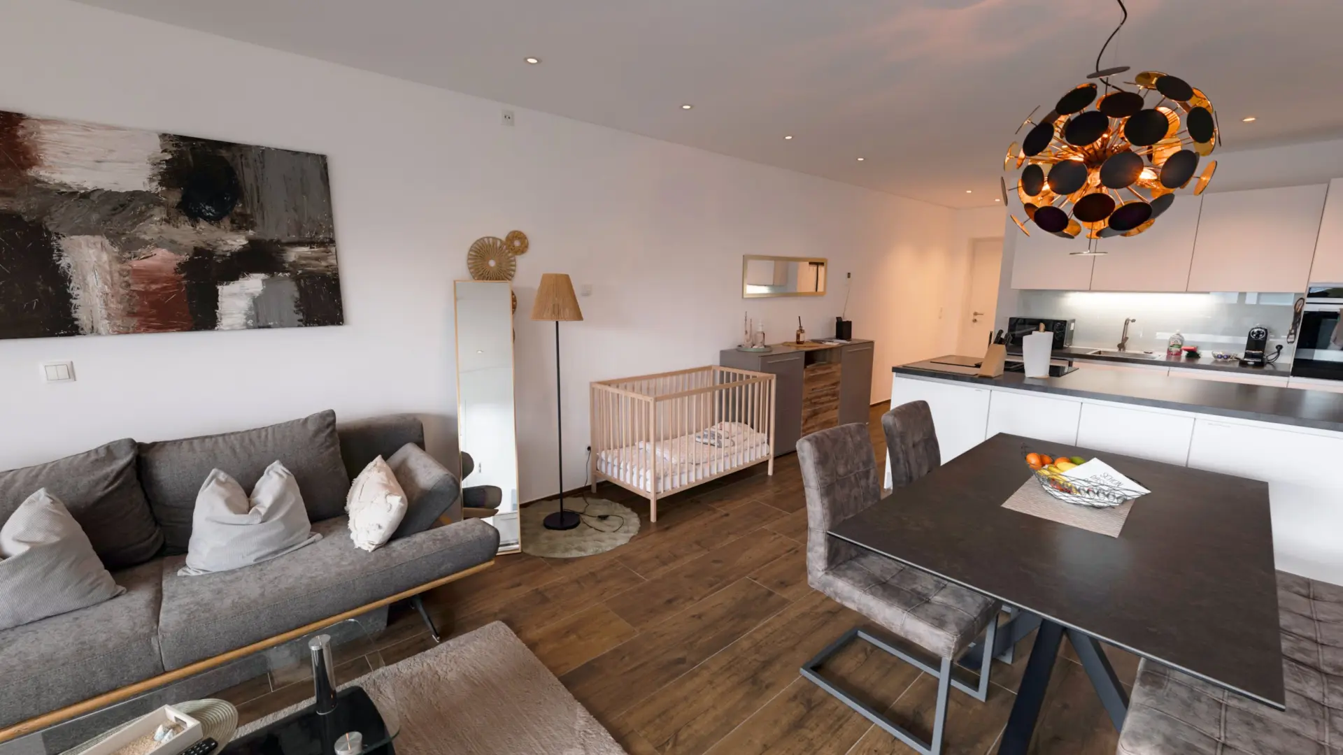 Modernes Wohnzimmer mit Küche und Kinderbett